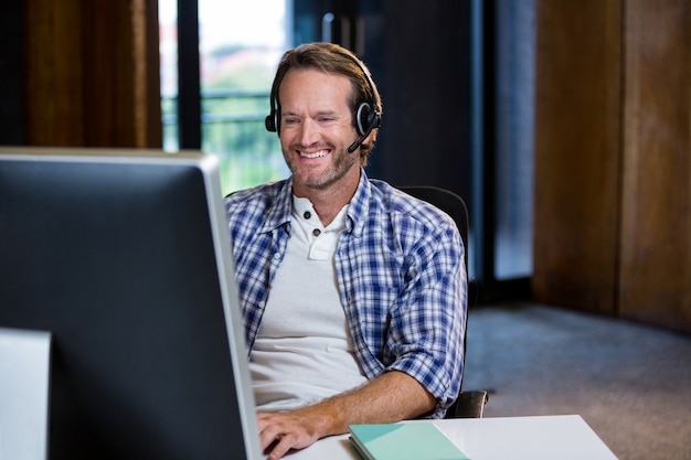 Creatieve zakenman die terwijl het werken aan computer glimlacht