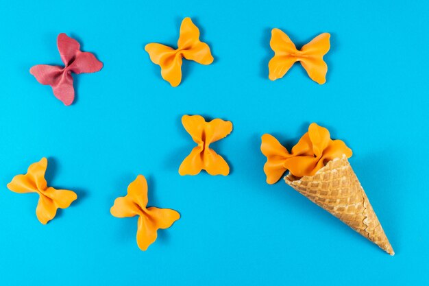 Creatieve zomer lay-out gemaakt van ijsje, wafel kegels en gekleurde pasta griesmeel papillon