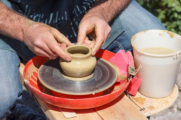 ろくろを使って手で粘土の壺を作成します。マスターは陶器の水差しを作ります