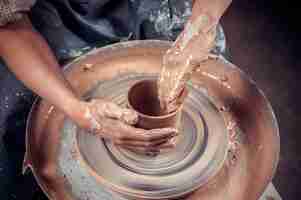 Photo creating a jar or vase. master crock. making clay jug. the sculptor in the workshop makes a jug out of earthenware closeup. potter's wheel. pottery concept.