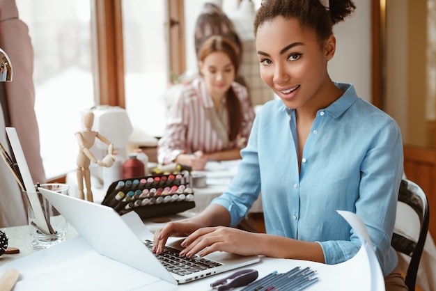 Creating new style. Two young attractive women working on new design project. African young woman in the foreground and caucasian one at the background