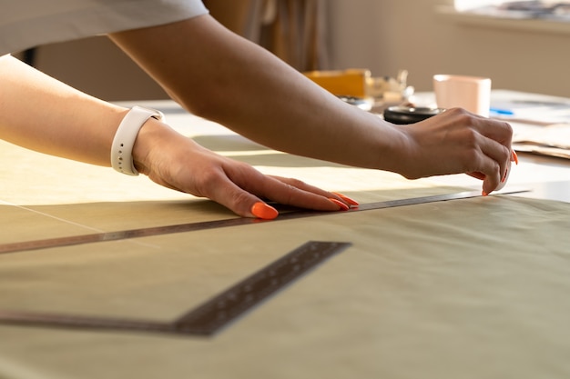 Создание модной одежды крупным планом женского дизайнера работает над черновиком ткани на швейном столе в студии