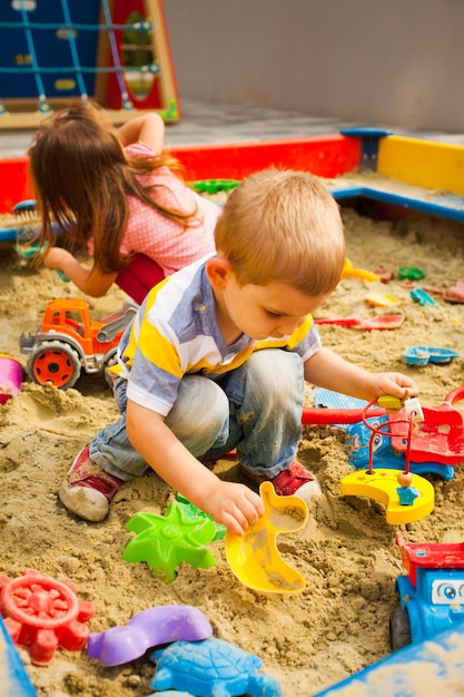 Creative activities for kids. Happy kids playing in sandbox outdoors.