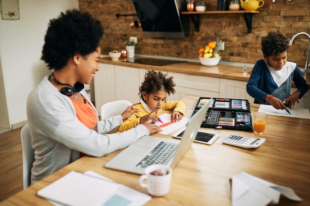 Creative African American kids drawing while their mother is working at home