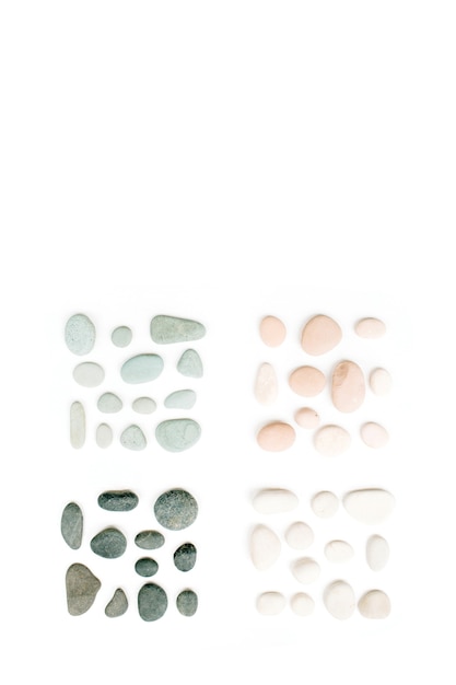 Photo creative arrangement of colored stones. mint, pink, beige and grey stones on white.