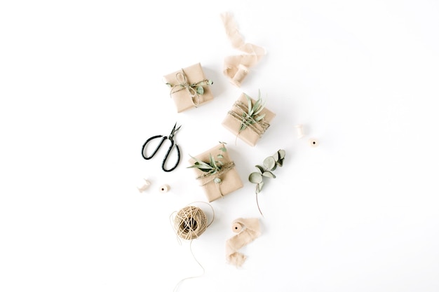 Creative arrangement pattern of craft boxes and green branches on white background.