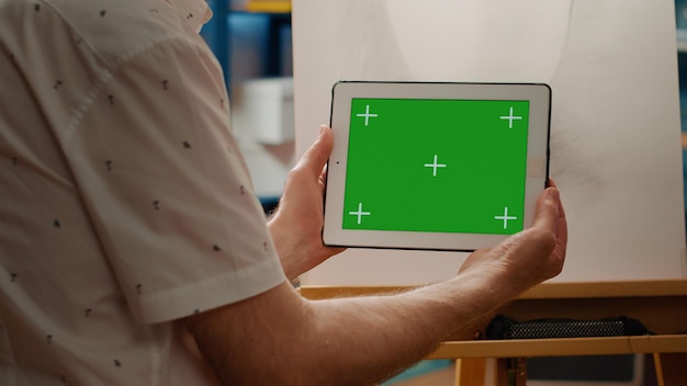 Creative artist looking at horizontal greenscreen on digital tablet to draw artwork masterpiece. Isolated mockup template with blank copyspace background and chroma key. Close up.