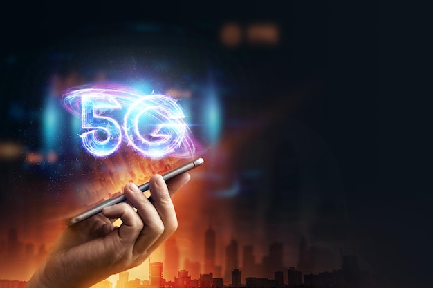 창의적인 배경, 한 남자의 손이 도시 배경에 5G 홀로그램이 있는 전화기를 들고 있습니다. 5G 네트워크 개념, 고속 모바일 인터넷, 차세대 네트워크. 혼합 매체.