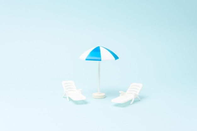 creative background with sunbeds and sun umbrella on pastel blue background