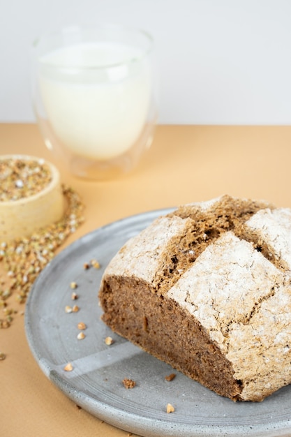 Creative beige background with green buckwheat bread and organic buckwheat milk. Harmless, wellness, gluten free healthy baking. Alternative bread. Copy spase