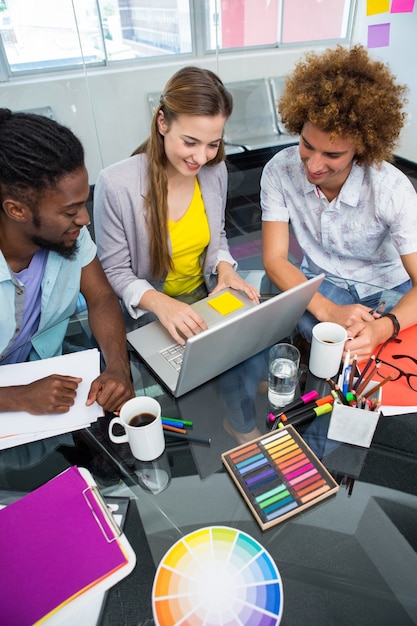 Creative business people using laptop at desk