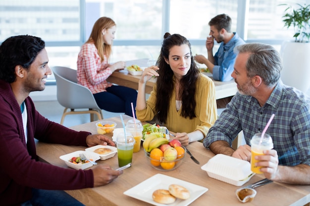 Creative business team discussing while having meal in office