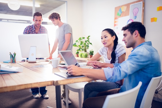 Creative business team gathered around laptops