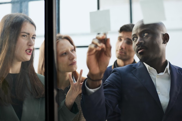 Creative business team looking at sticky notes on glass window