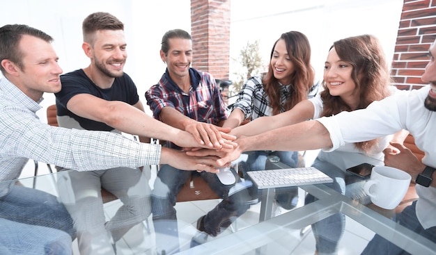 Creative business team putting hands together at the office