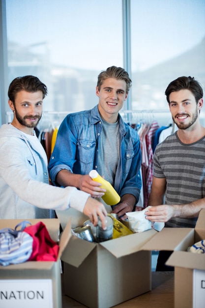 Creative business team sorting clothes in donation box in office