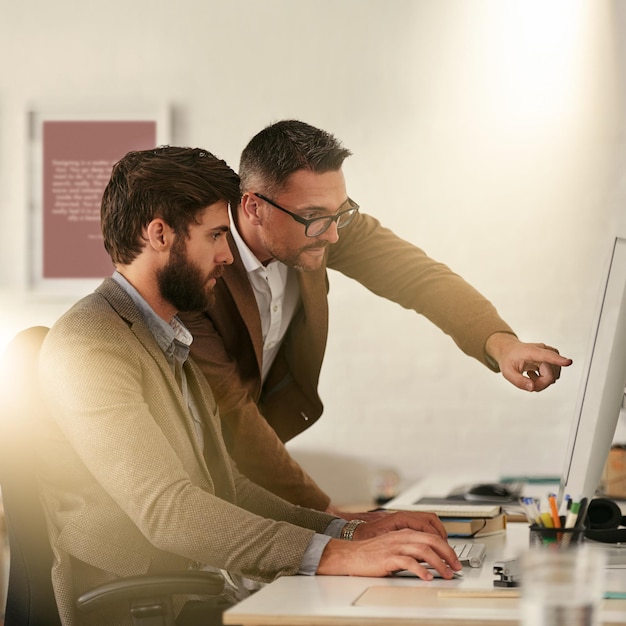 creative businessman team and coaching intern on computer in web design ux or ui at the office man designer training staff or student on pc for teamwork support help or startup at the workplace