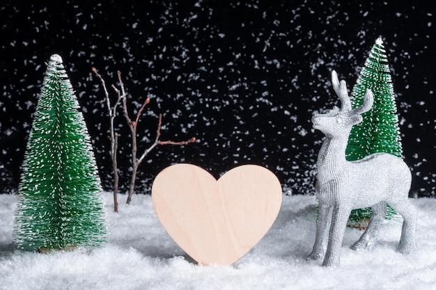 夜の降雪の中でおもちゃの木から創造的なクリスマス カード クラフト木製の心とクリスマスの鹿
