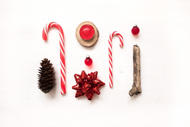 Creative christmas flat lay composition with pine cones, candy canes, gift bow, glass ball