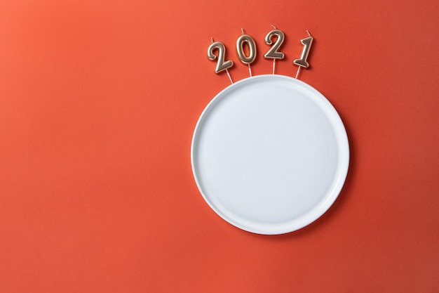 写真 クリスマス・テーブル・セッティング: 数字の形で空の皿のキャンドル 2021年モデル