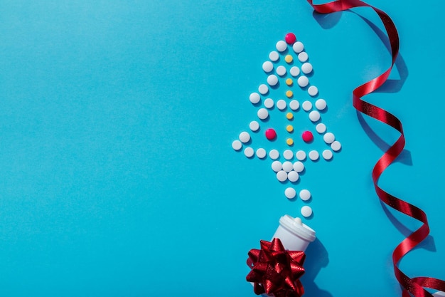 Creative Christmas tree made of pills on blue background Holiday greeting card with space for text