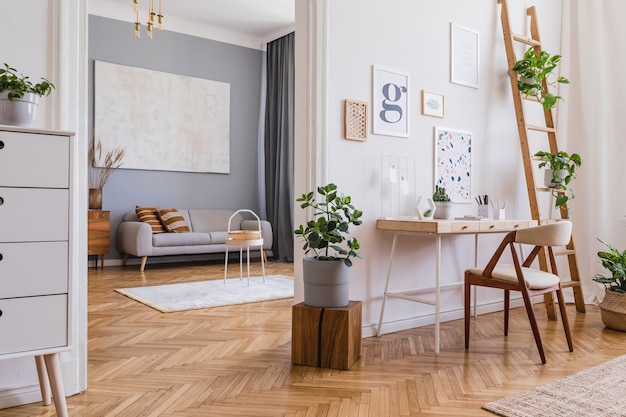포스터 프레임, 나무 책상, 의자, 식물 및 액세서리를 모의로 한 세련된 스칸디 홈 오피스 인테리어 디자인의 창의적인 구성. 중립 벽, 쪽모이 세공 마루 바닥. 주형.