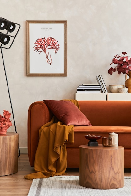 モックアップポスターフレーム、オレンジ色のソファ、ベージュのコンモード、コーヒーテーブル、スタイリッシュなパーソナルアクセサリーを備えたスタイリッシュなリビングルームのインテリアのクリエイティブな構成。芸術的な空間。レンプレート。