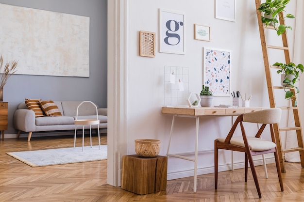 Creative composition of stylish scandi home office interior design with mock up poster frames, wooden desk, chair, plants and accessories. Neutral walls, parquet floor. Template.