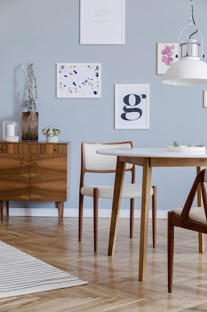 포스터 프레임, 나무 옷장, 의자, 식물 및 액세서리를 모의로 한 세련된 스칸디 거실 인테리어 디자인의 창의적인 구성. 중립 벽, 쪽모이 세공 마루 바닥. 주형.