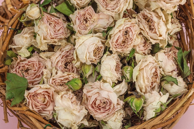 Creative composition with dry delicate roses in homemade wicker basket