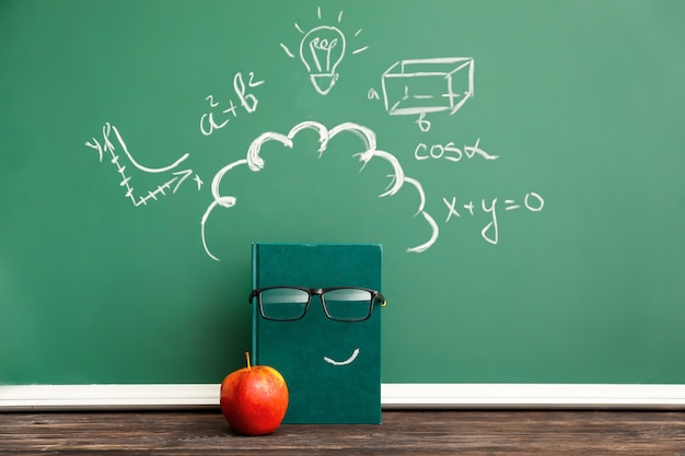 Creative composition with notebook, apple and school blackboard