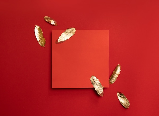 Creative composition with red leaf frame with gold leaves on a red background.