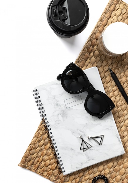 Творческая композиция с солнцезащитные очки, планировщик, косметика и соломенная салфетка на белом фоне