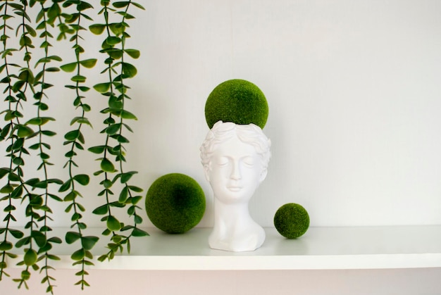 Creative concept colorful plaster sculpture of female face on green plants Concept of minimal artistic fantasy