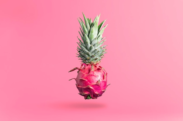 Creative concept of food art Dragon fruit with pineapple tops on a pink background Exotic fruit concept