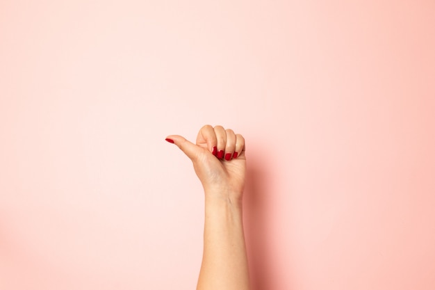 Creative concept of likes and remops of social networks Closeup of female hand showing thumbs up sign on a pink 