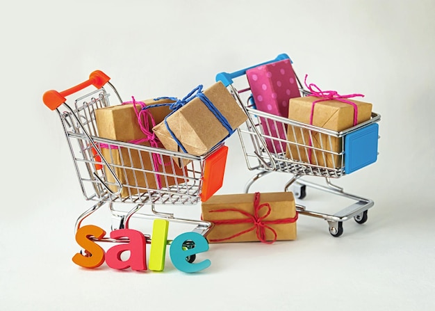 Creative concept of shopping carts with wrapped gifts on light background, selective focus.