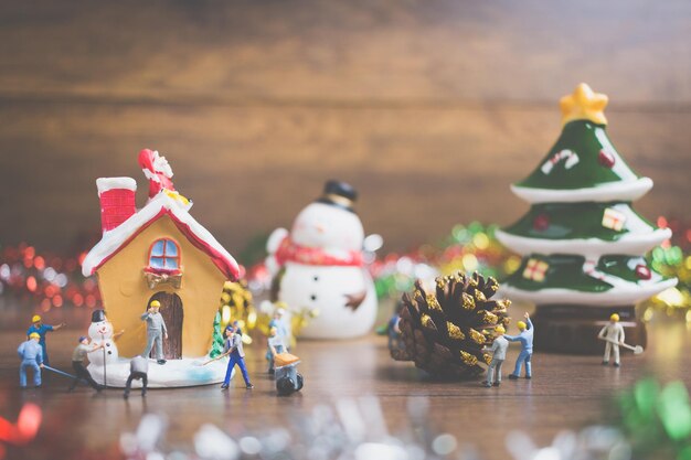 Creative concept with miniature people creating Christmas decorations on a wooden background