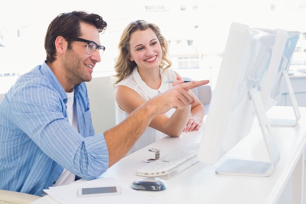 Creative designer talking to his colleague sitting at the desk