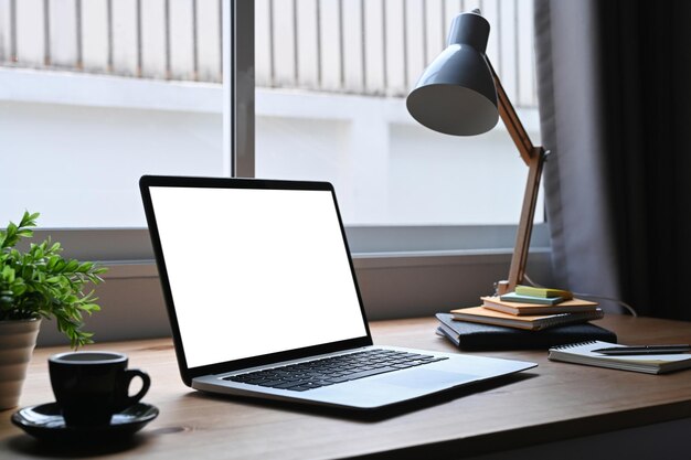 Creative designer with laptop coffee cup supplies and other items on wooden table