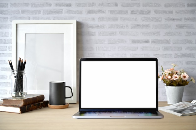 Creative desk workspace with blank picture frame poster, blank screen laptop 