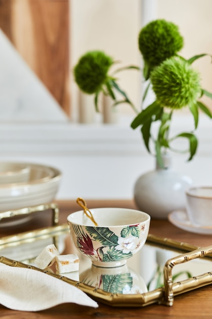 Creative and elegant dining room composition with classy porcelain, golden tray and beautiful personal accessories. Luxury apartments. Beauty in the details. Template.