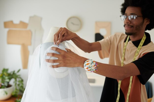 창의적인 패션 디자이너는 드레스 작업 시 마네킹에 얇은 명주 그물 천을 입힙니다.
