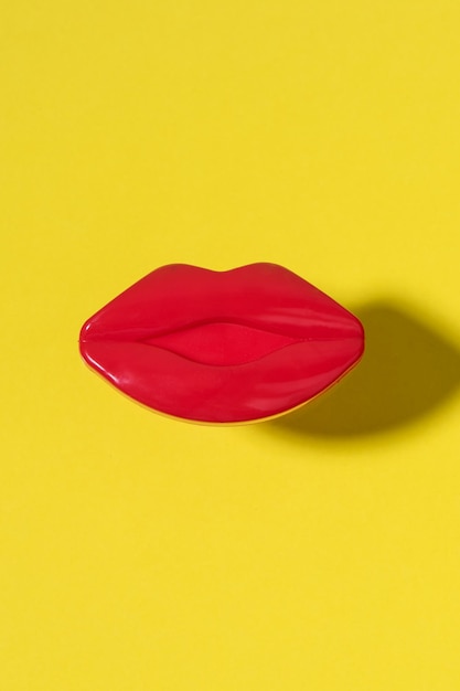 Foto labbra rosse femminili creative su sfondo giallo. concetto di bellezza minimale.