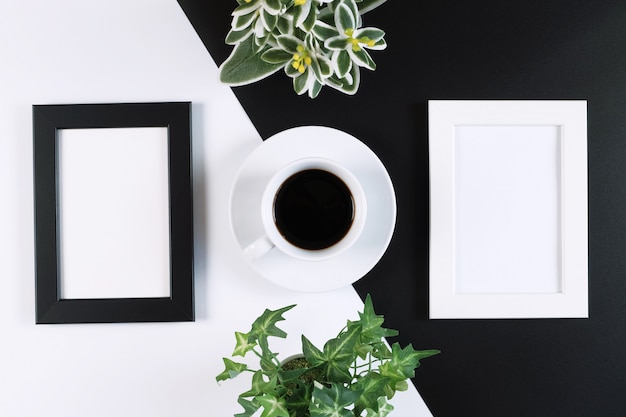 Creative flat lay of coffee mug, empty photo frames, and plants