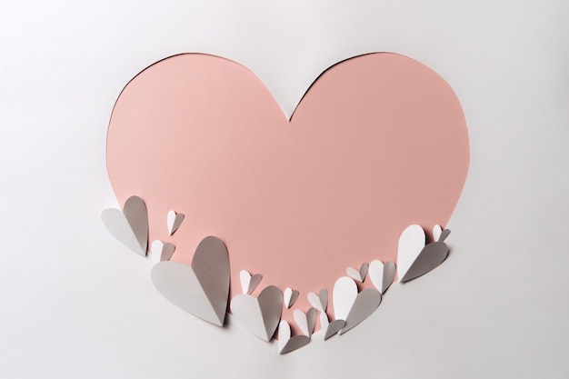 Creative flat lay of  heart shaped paper frame on soft color wall.