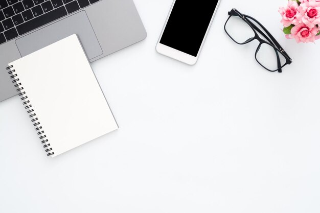 Photo creative flat lay photo of workspace desk top view office desk with laptop glasses phone notebook and plant on white color background top view with copy space flat lay photography