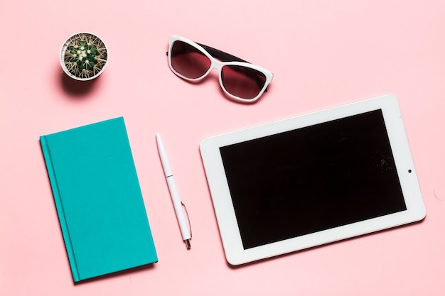 Creative flat lay photo of workspace desk with aquamarine notebook eyeglasses cactus with copy space pink background minimal style