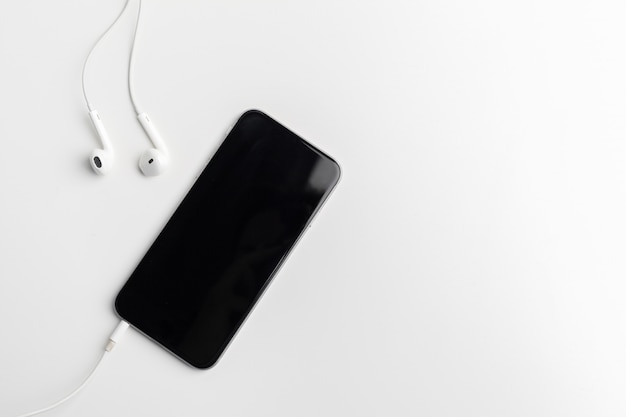 Creative flat lay photo of workspace desk with earphones and mobile phone