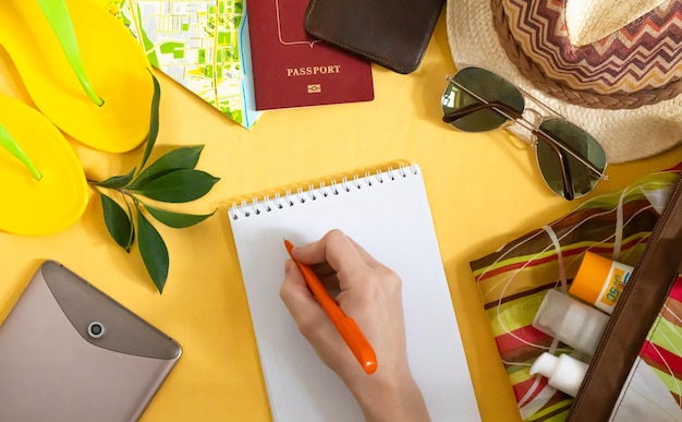 Creative flat lay of summer accessories supplies for travel preparation on yellow background